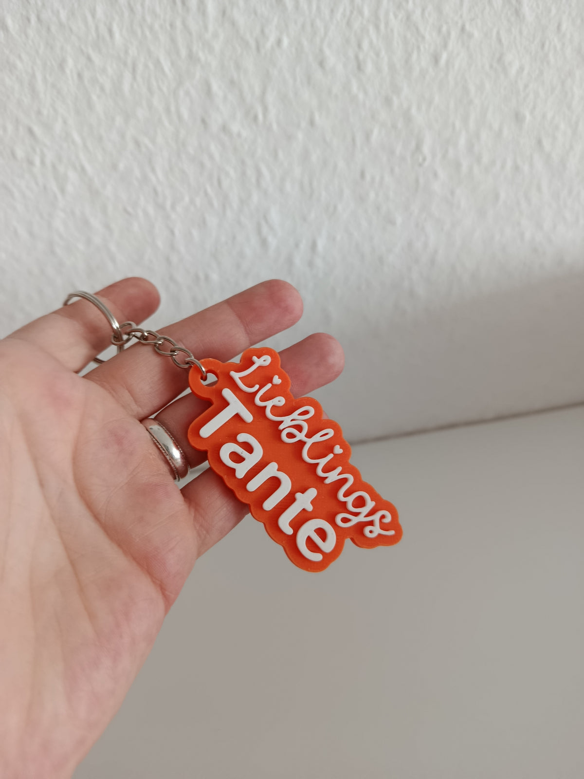 Orangefarbener Schlüsselanhänger Lieblings Tante in einer Hand gehalten, mit weißer Schrift und Metallring