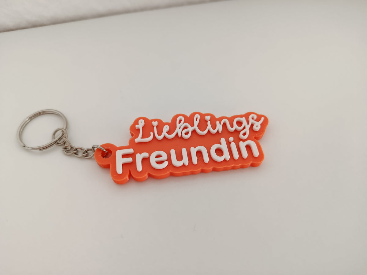 Orangefarbener 3D-Schlüsselanhänger mit der Aufschrift Lieblings Freundin auf hellem Hintergrund